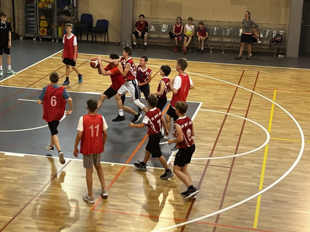 žáci hrají basketbal ve sportovní hale na bazéně