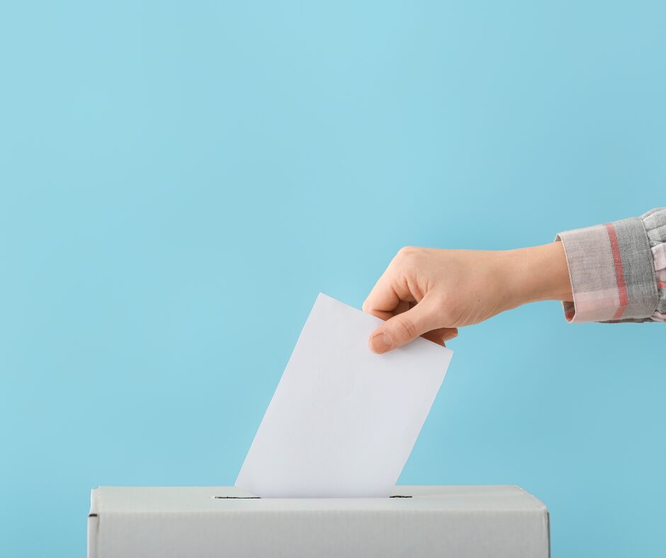 Ilustrační obrázek - ruka vhazuje obálku do volební urny
